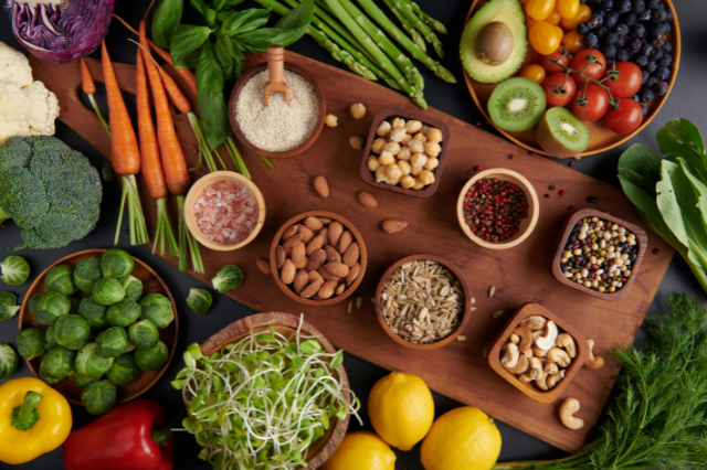 A vibrant, fresh, top-down photograph of various brain-healthy foods arranged beautifully on a clean wooden surface. Included are dark blue blueberries, whole and cracked walnuts, green leafy spinach, and a few rich dark chocolate pieces. The natural lighting and composition convey a sense of health, vitality, and the nutritional foundation for experiencing what a sharp mind feels like. Minimalist and appetizing presentation.