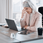 A professional woman in her 50s experiencing midday fatigue at her desk after lunch, illustrating the common biological cognitive slump.