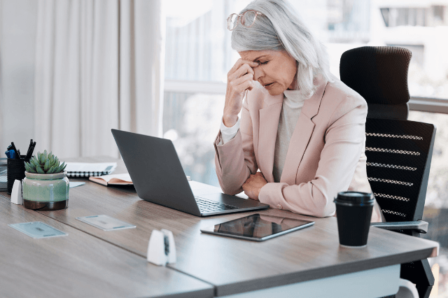 A professional woman in her 50s experiencing midday fatigue at her desk after lunch, illustrating the common biological cognitive slump.