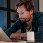 Man in his late 40s staring at a laptop with an unfocused expression at a modern home office desk, illustrating the experience of declining focus and concentration after 40.