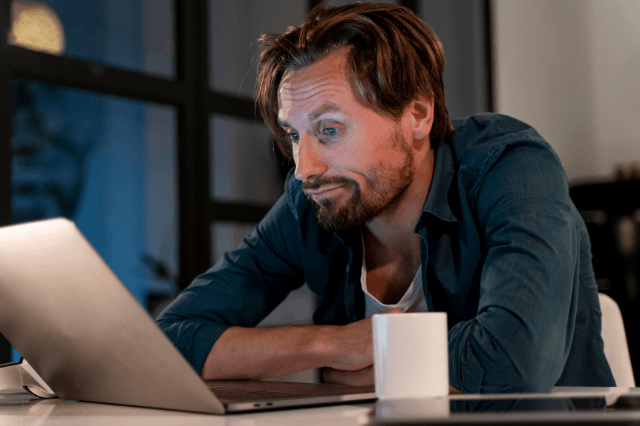 Man in his late 40s staring at a laptop with an unfocused expression at a modern home office desk, illustrating the experience of declining focus and concentration after 40.