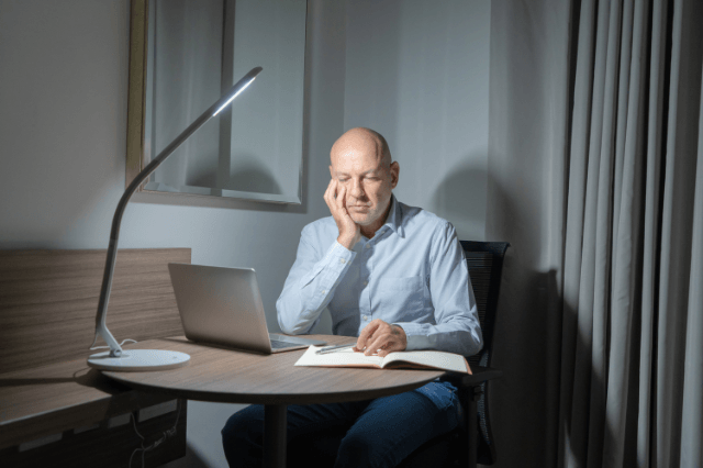 Man in his 50s with eyes closed and hands on temples at a home office desk, illustrating the difference between true forgetfulness and cognitive exhaustion affecting memory and recall.