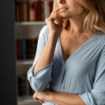 A woman in her late 40s experiencing a momentary memory slip in a modern kitchen, illustrating the reality of perimenopause brain fog.