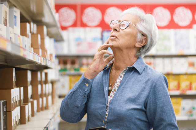 A woman in her late 60s experiencing a sudden memory blank at a social gathering, illustrating the silent progression of cognitive depletion.